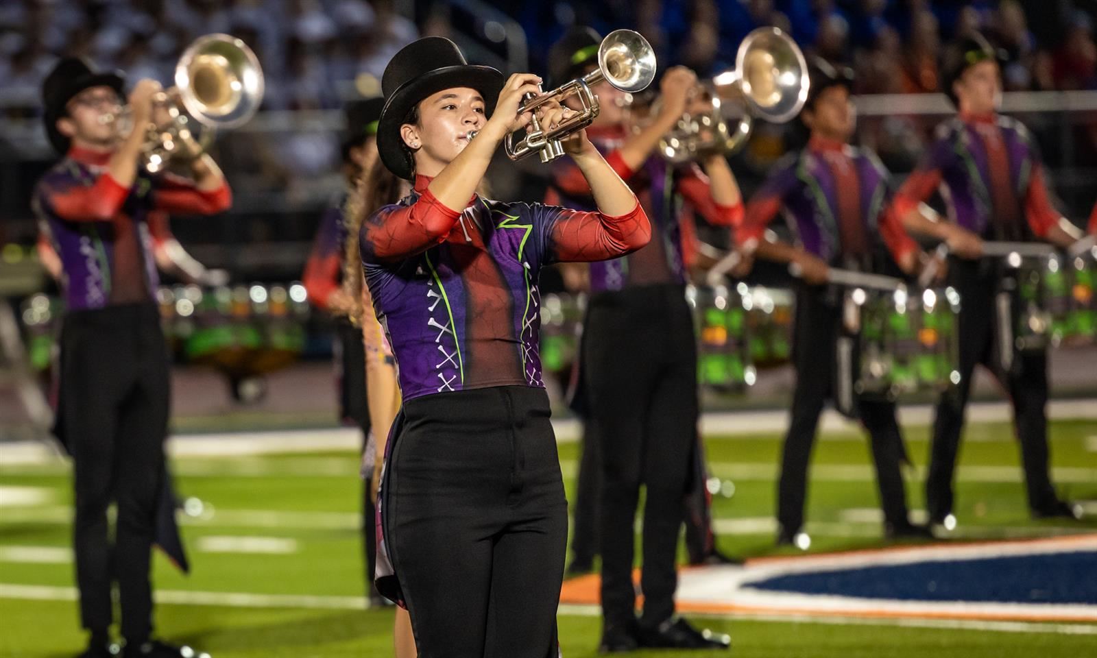 Students play trumpet on the football field